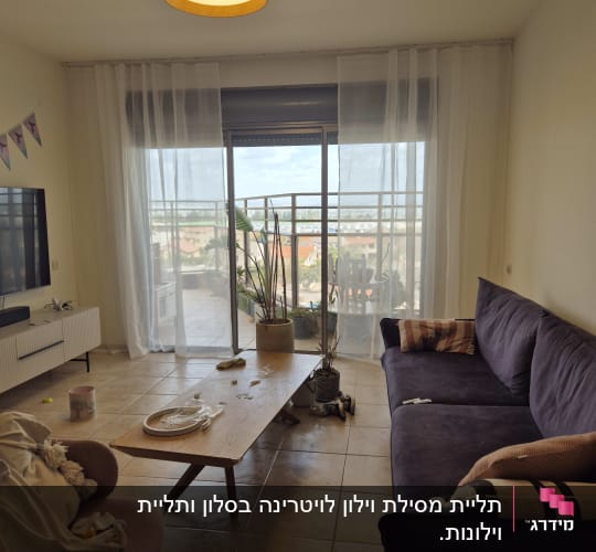 סלון עם ספה, שולחן, וצמחים ליד חלון גדול